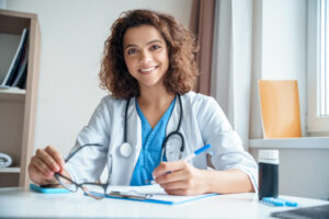 Smiling doctor at her desk, who understands the importance of financial advice for physicians.