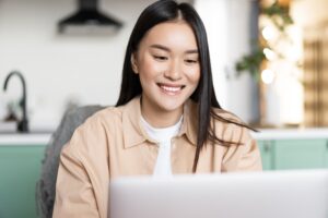 Asian medical student smiles at her computer screen while taking online CME courses